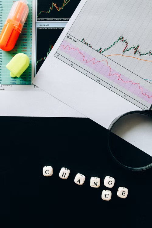 CHANGE spelled in wooden letter dice next to a printed stock chart and magnifying glass, symbolizing India's CSR initiatives driving trust and impact.